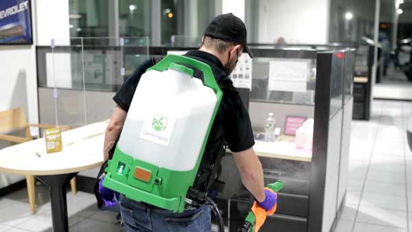 Germ Hero Technician Disinfecting Car Dealership Showroom